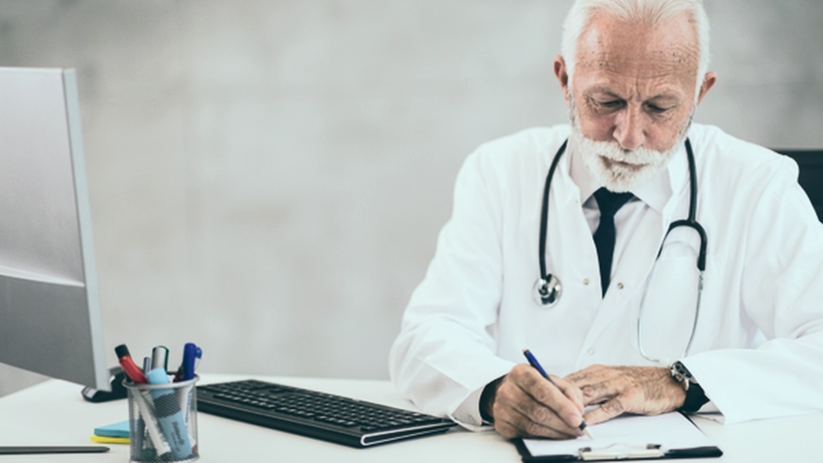 Médico do trabalho revisando e preenchendo documentação técnica de saúde ocupacional