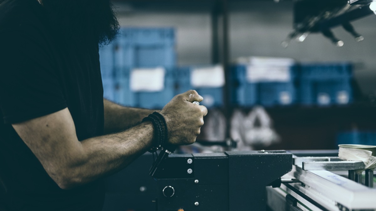 Trabalhador industrial operando máquina em ambiente de produção, ilustrando tempo de exposição ocupacional